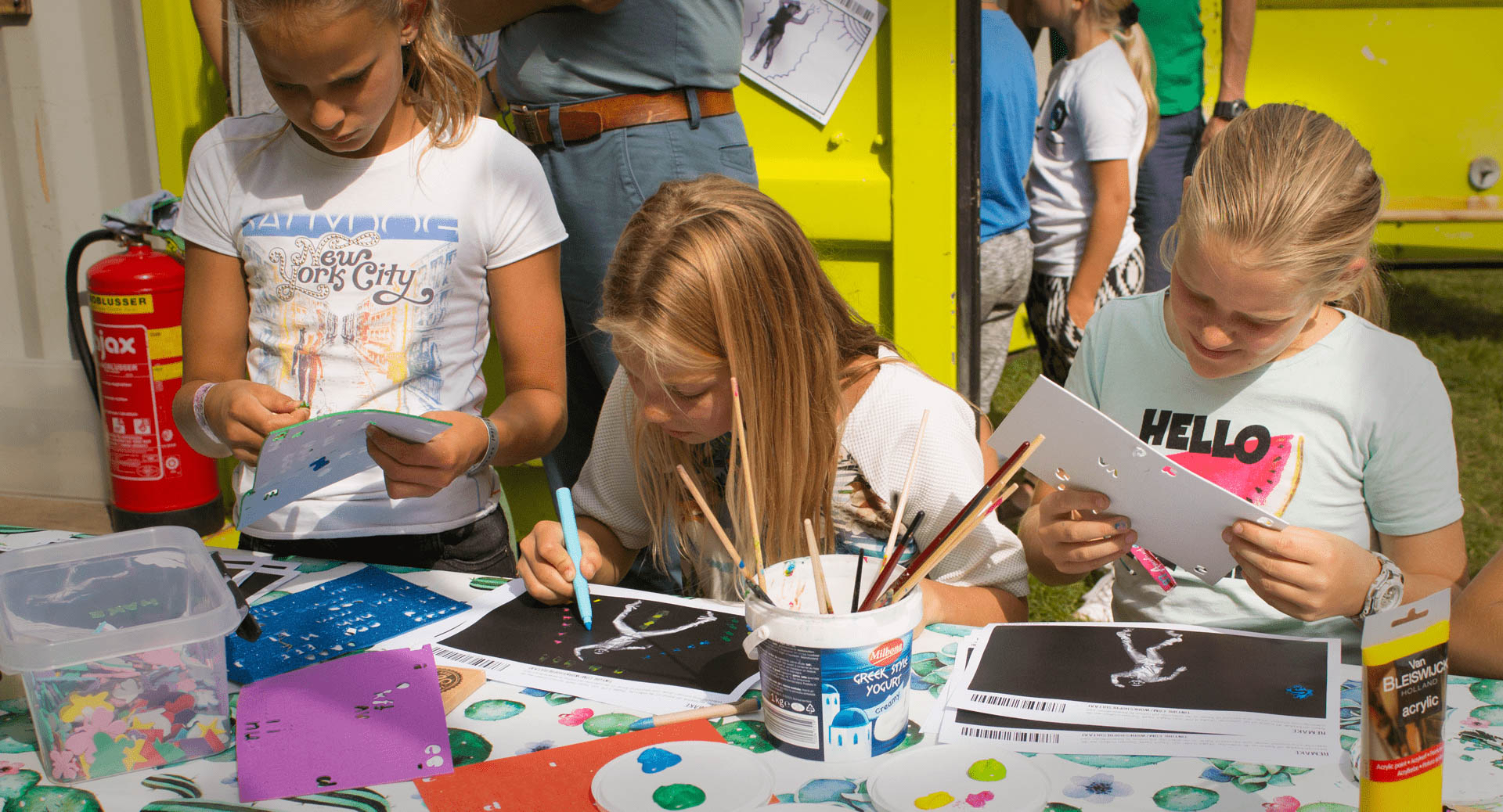 Kinderen bewerken frames van pop videoclip handmatig met verf, stiften en stickers op een zomer festival voor een gezamelijke kleurige stop motion animatie.