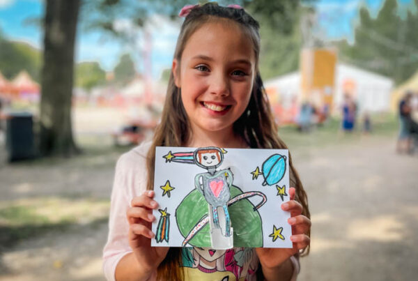 Kind toont op een festival trots zelfgebouwde mechanische automata die een figuur laat bewegen door techniek.